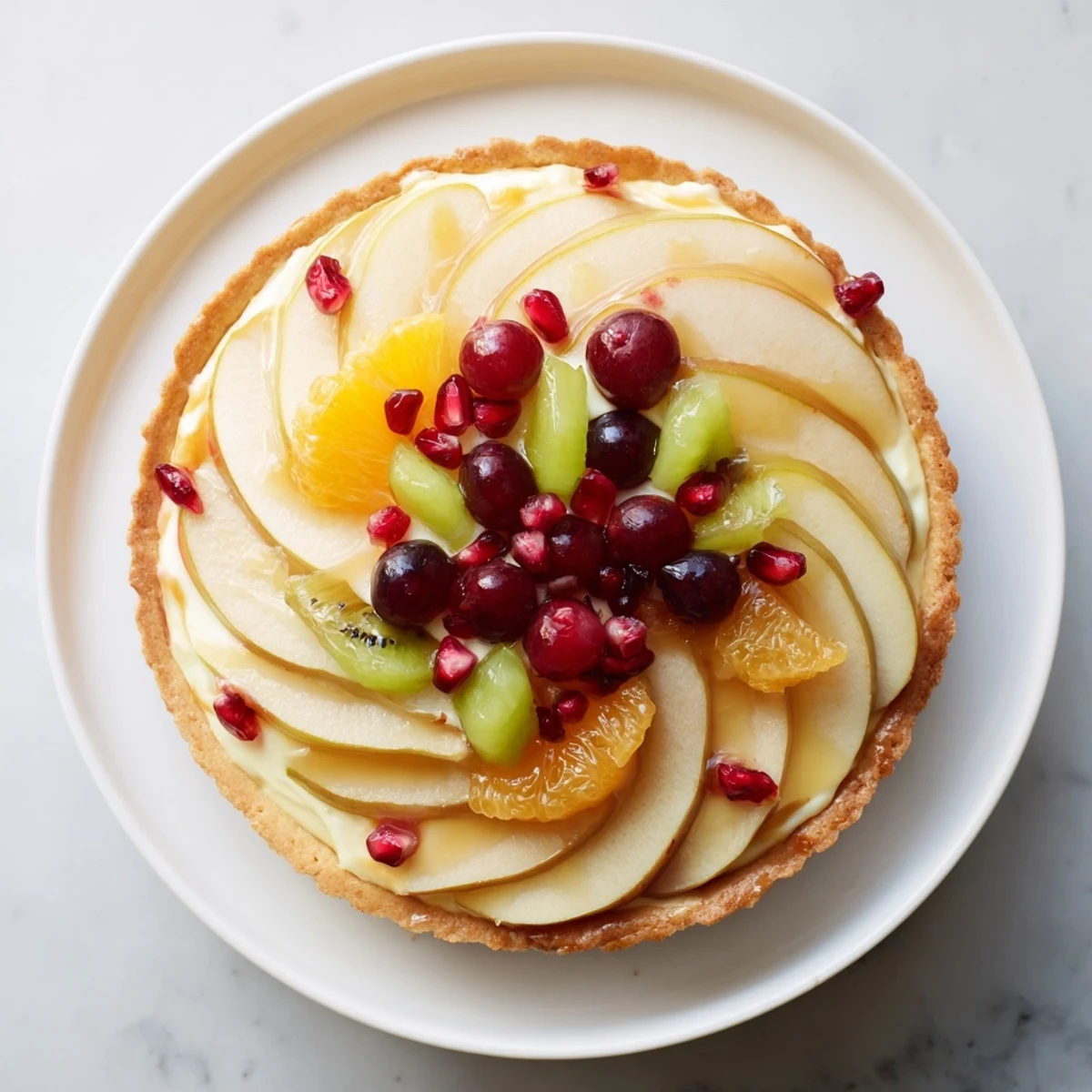 The beautiful Winter Fruit Tart presents a colorful array of fresh, seasonal fruit slices, ready to enjoy.