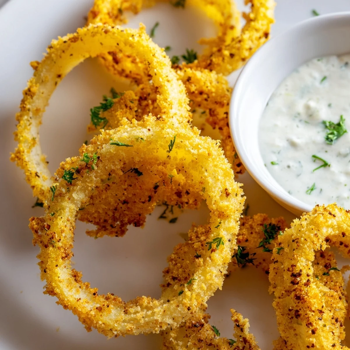 Golden, crispy baked onion rings piled high with creamy ranch dip for dipping.