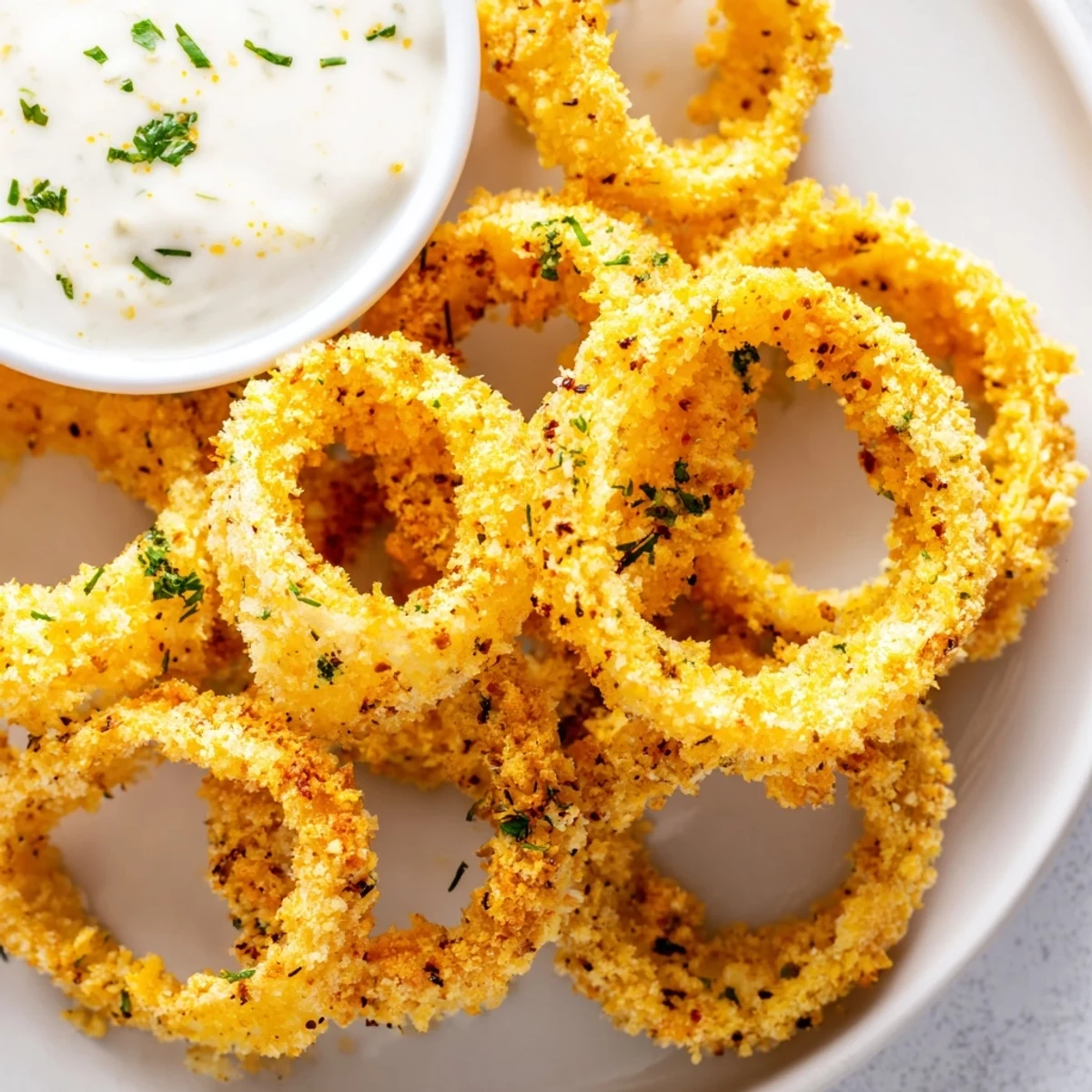 Freshly baked onion rings, a homemade American appetizer, served alongside a cool ranch.