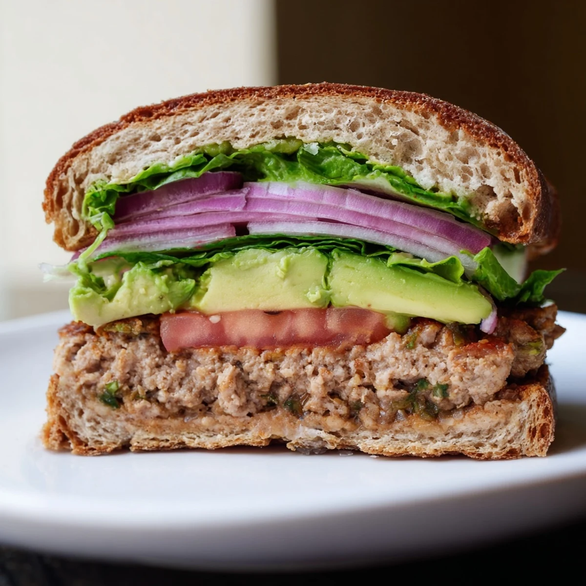 Creamy avocado slices garnish the turkey burger, paired with a fresh salad and sweet potato fries for a balanced meal.