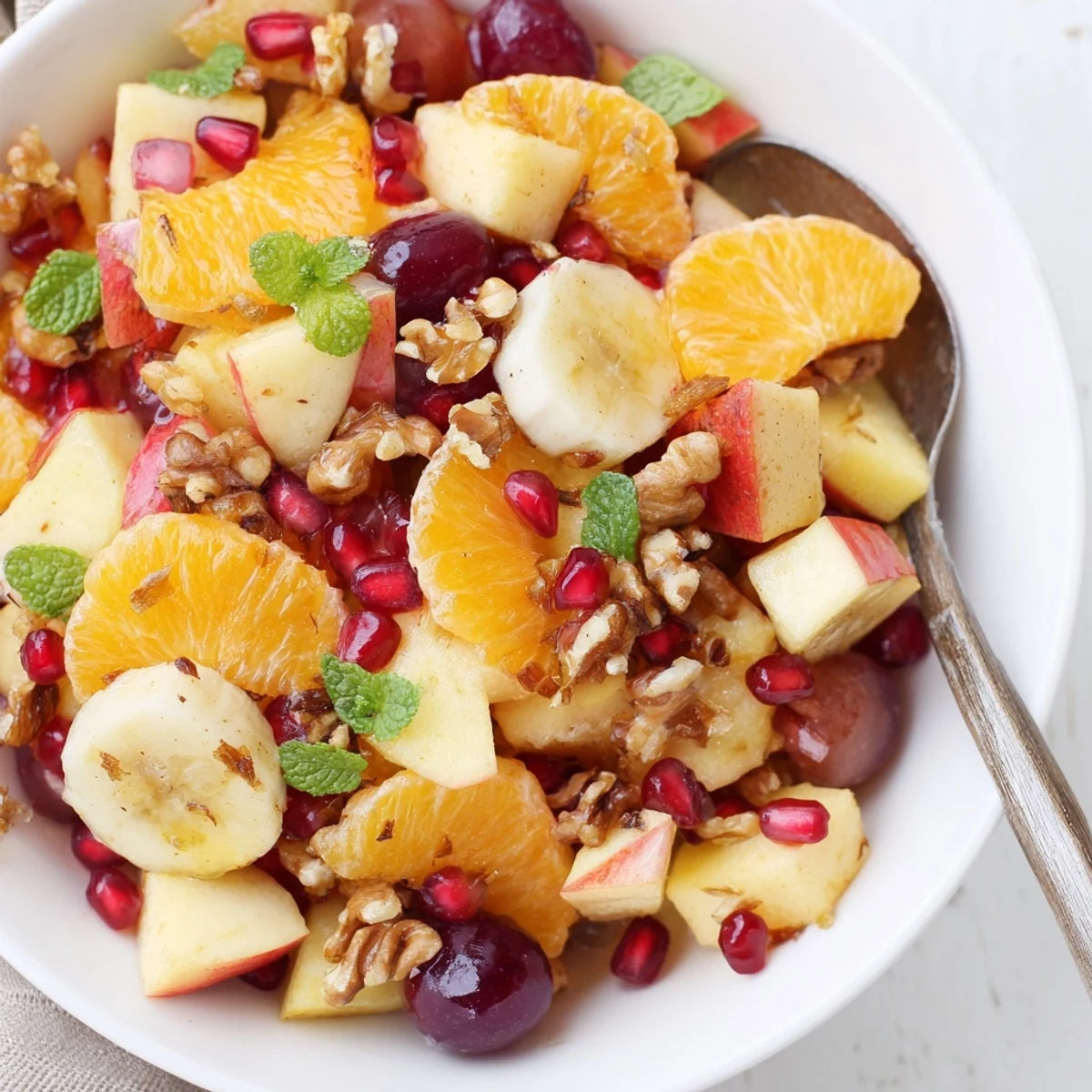 Close-up view of Winter Fruit Salad with Citrus in a glass bowl, highlighting glossy grapefruit segments, sliced pears, and glistening pomegranate arils ready to serve.