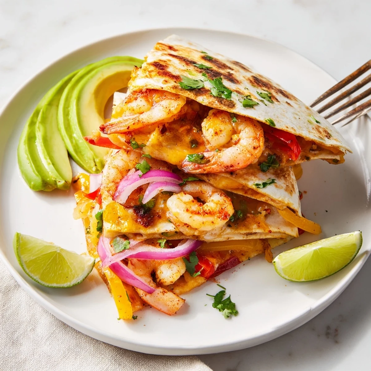 Overhead view of plated Shrimp Fajita Sheet Pan Quesadillas with fresh lime wedges and creamy dipping sauce.