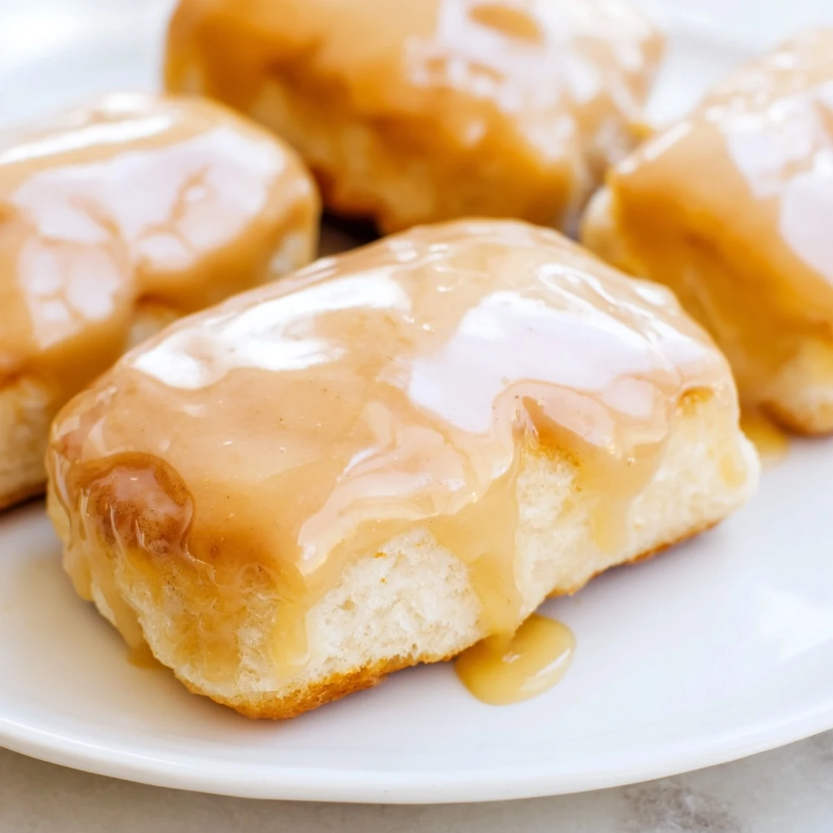 Freshly fried Maple Donut Bars arranged on parchment paper, ready to be dipped into a warm, homemade maple glaze.