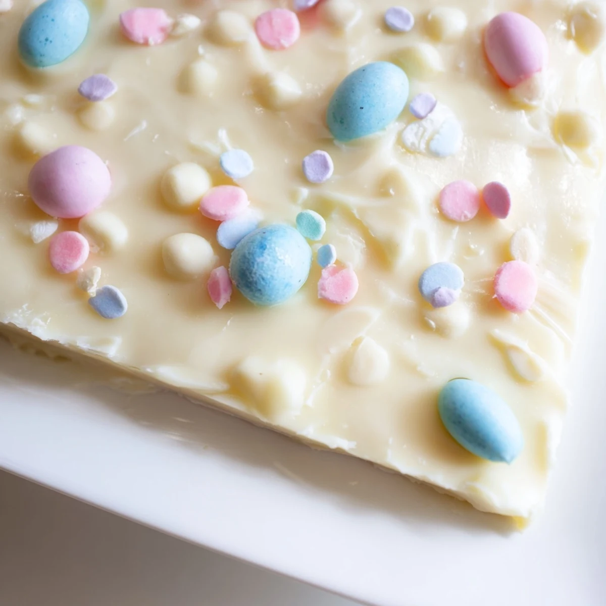 Creamy white chocolate Easter Fudge with pastel candies scattered across a chilled square pan.
