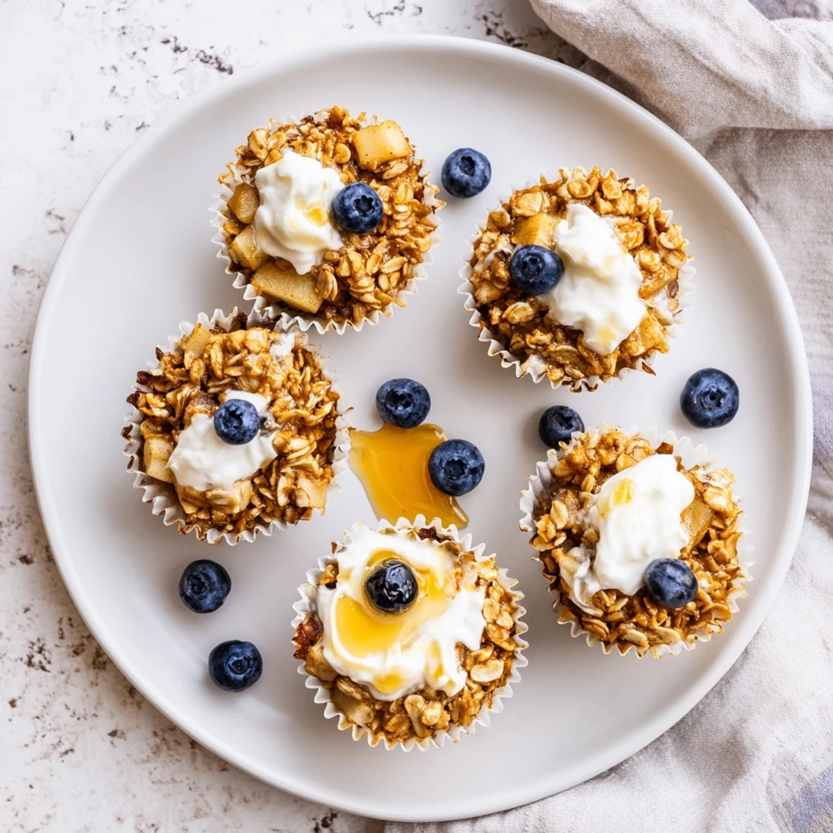 Healthy baked oatmeal cups served with Greek yogurt and a drizzle of honey for a delicious breakfast.