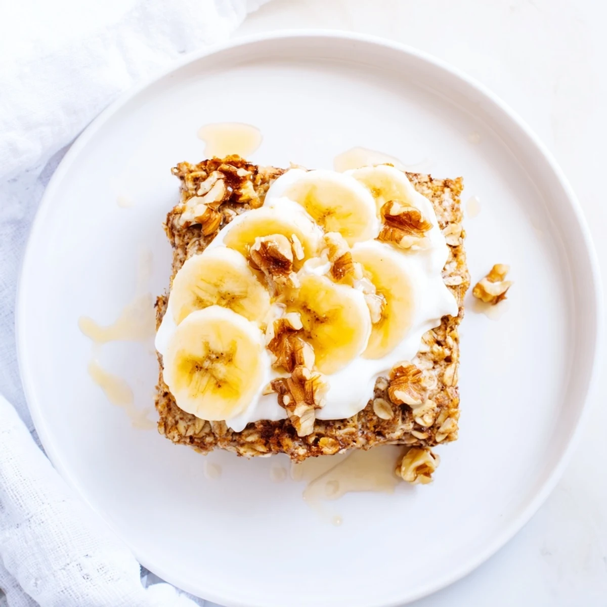 A warm slice of Banana Baked Oatmeal drizzled with honey, served alongside a cup of coffee. 