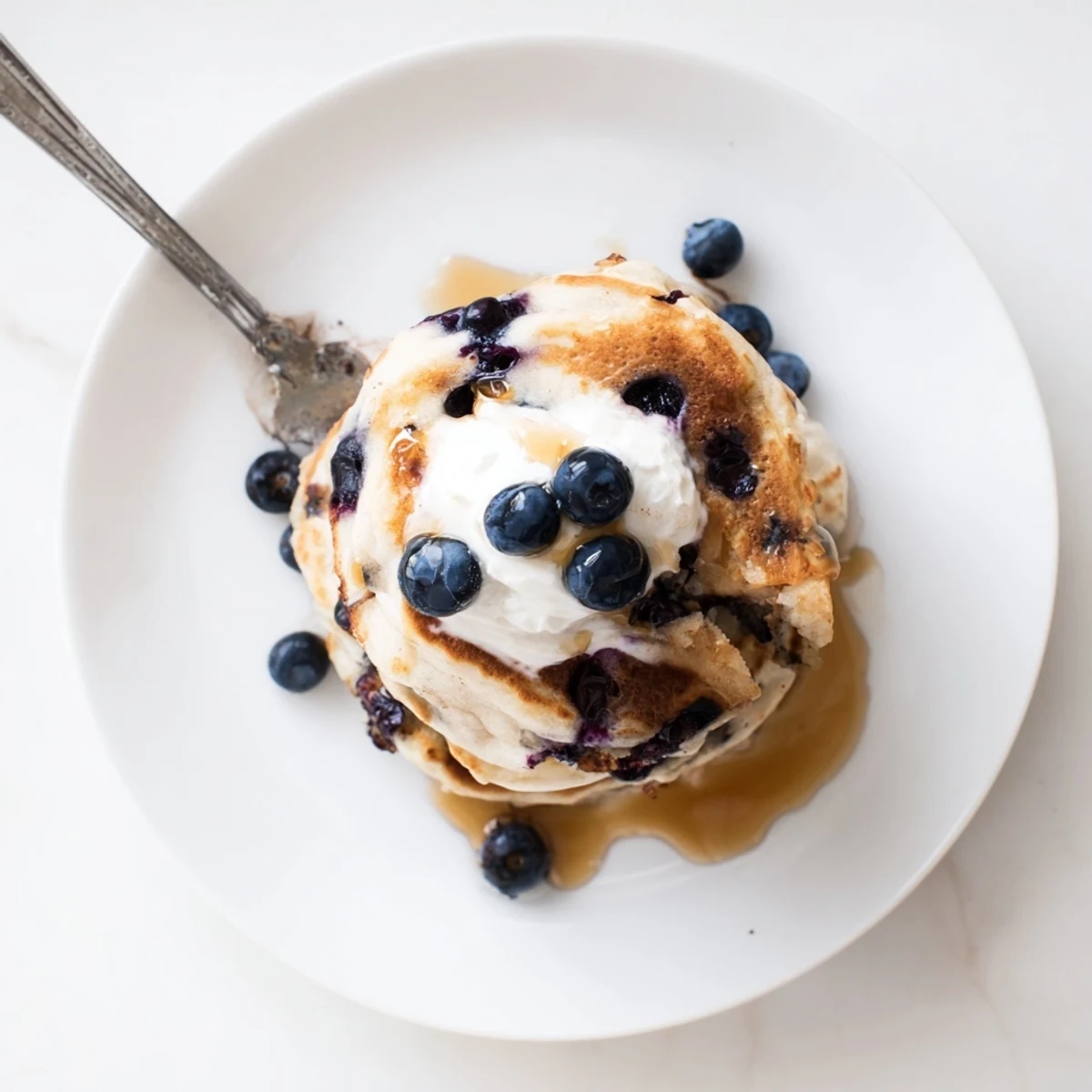 Stack of Greek Yogurt Blueberry Pancakes served with creamy yogurt and blueberries, fluffy texture visible in warm morning light.