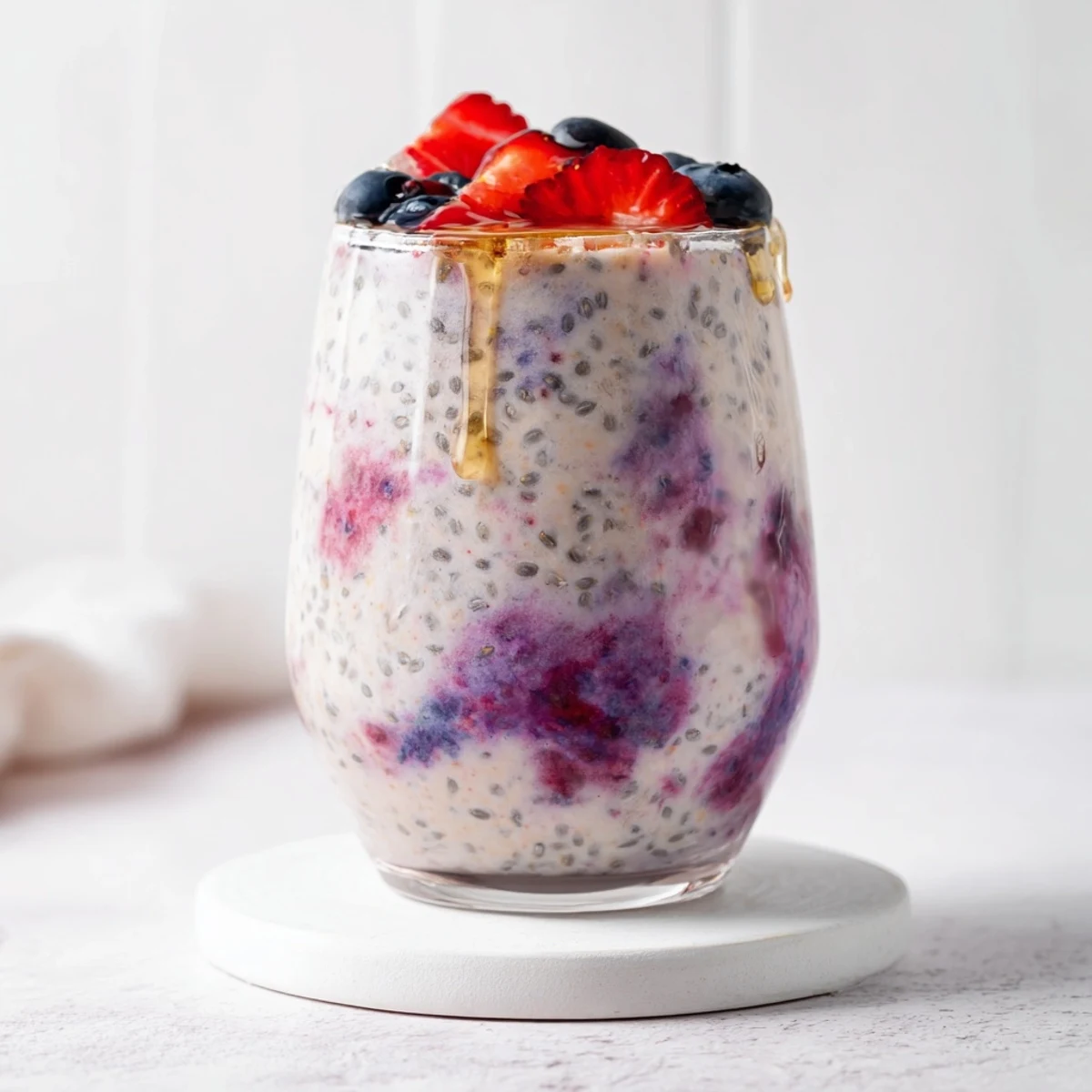 Vibrant purple Greek yogurt breakfast smoothie poured into a glass with berry garnish