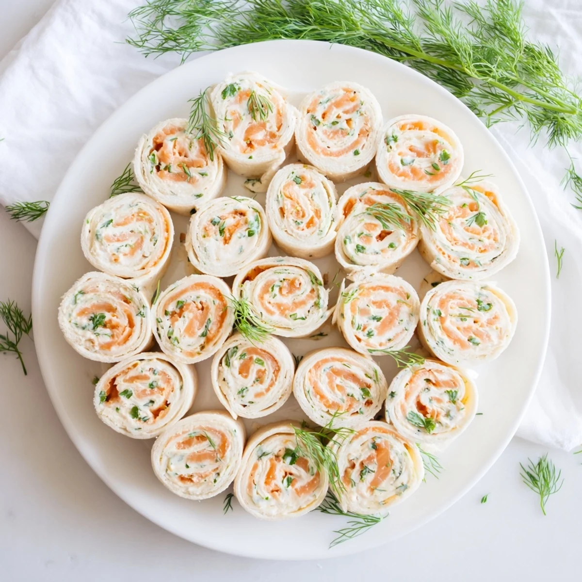 Delicious spiral sliced smoked salmon roll ups topped with green herbs ready for gluten-free lunch service