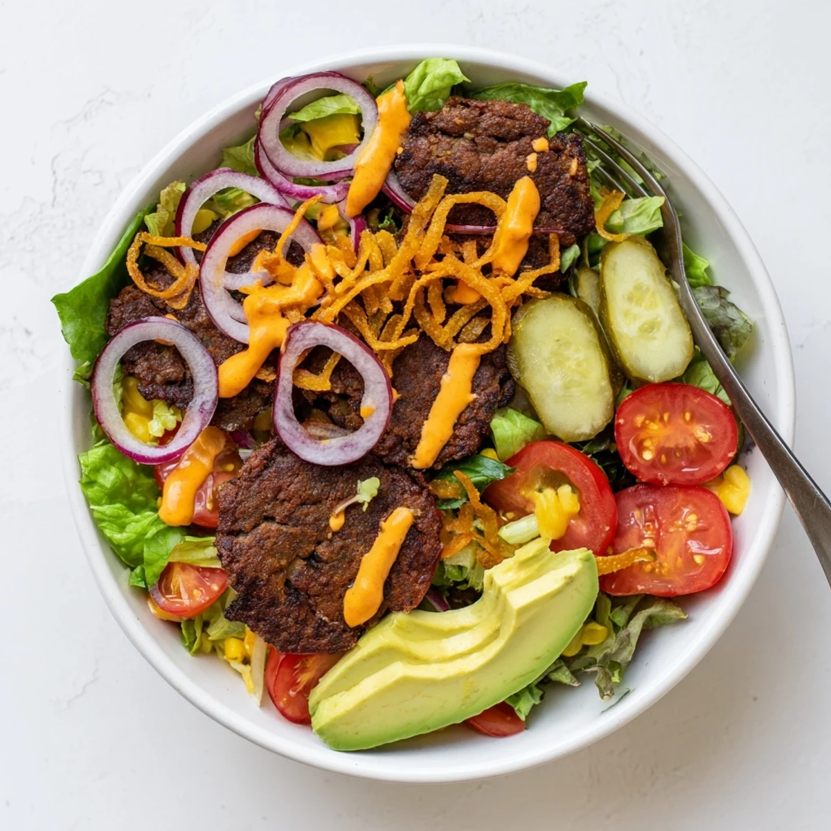 Golden crispy smash burger patties arranged over fresh salad greens with colorful toppings