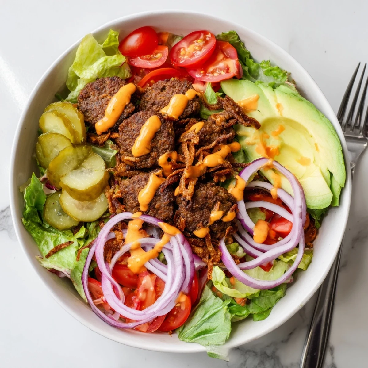 Deconstructed burger bowl with smashed beef patties, fresh vegetables, and cheddar cheese