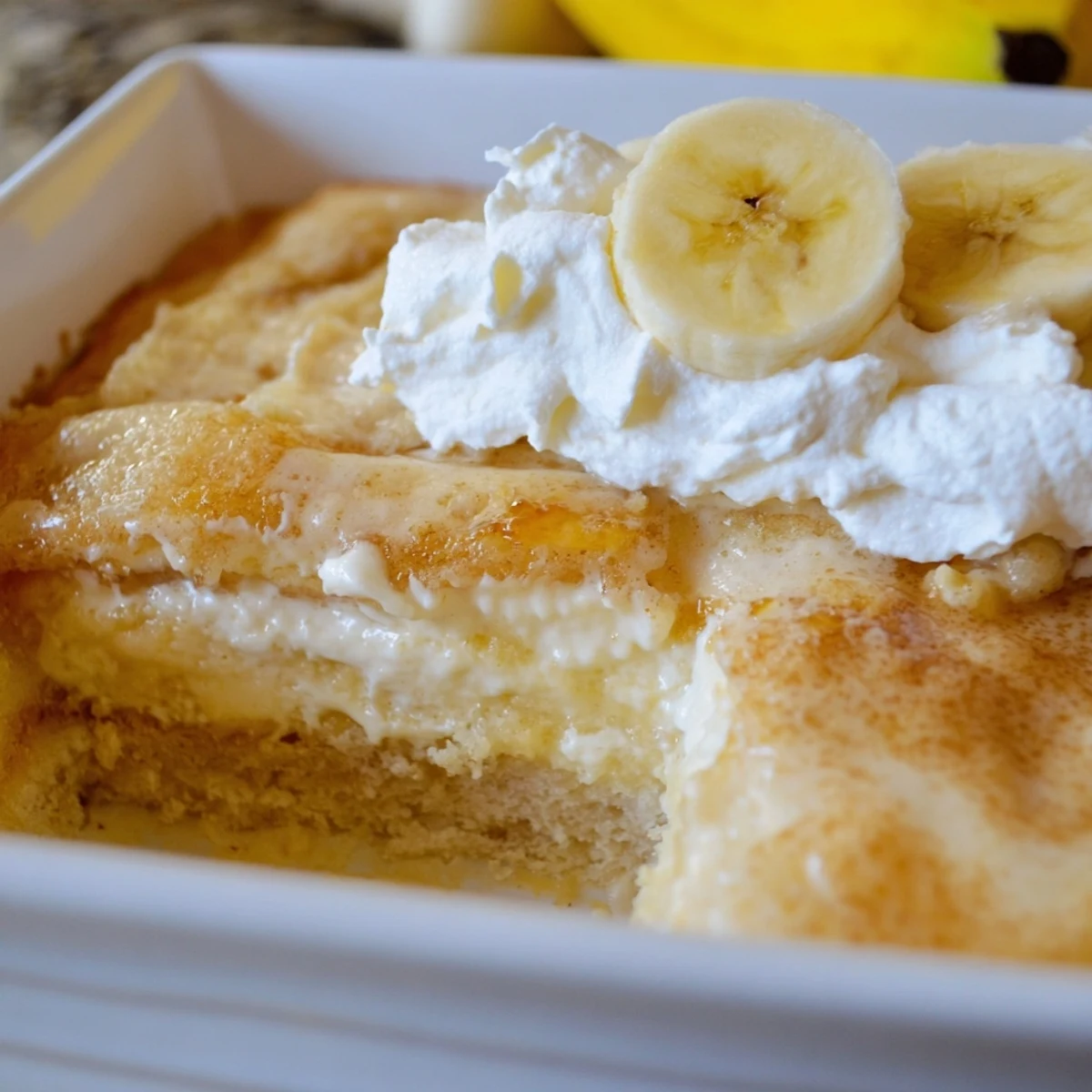 Sliced bananas layered between creamy cheesecake and pudding in this Southern comfort dessert dump cake