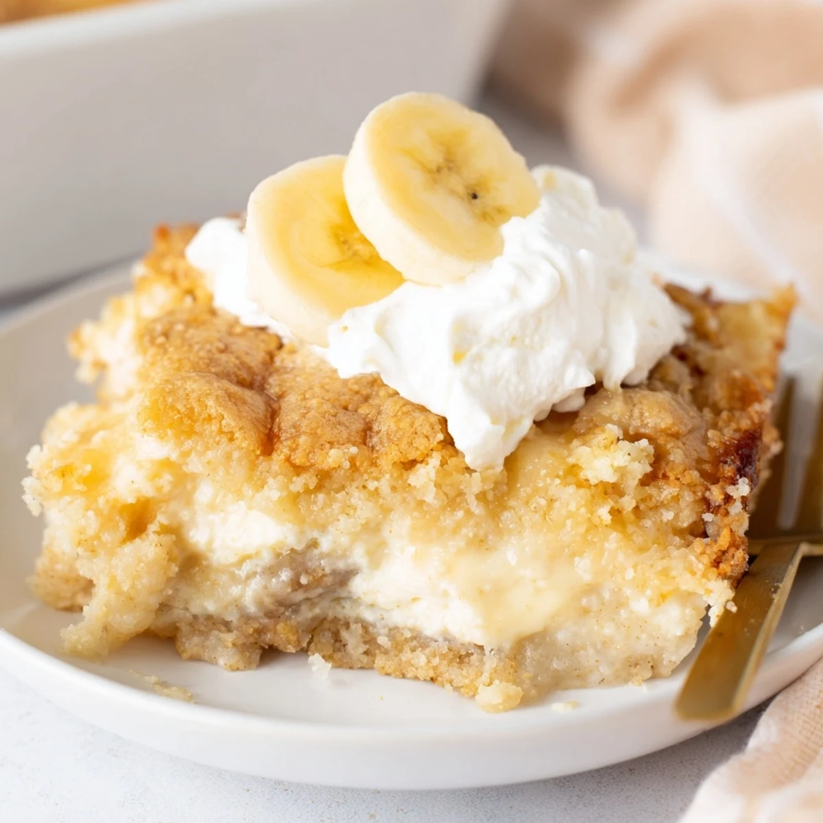 Rich creamy cheesecake and banana pudding layers beneath buttery golden cake crumble topping