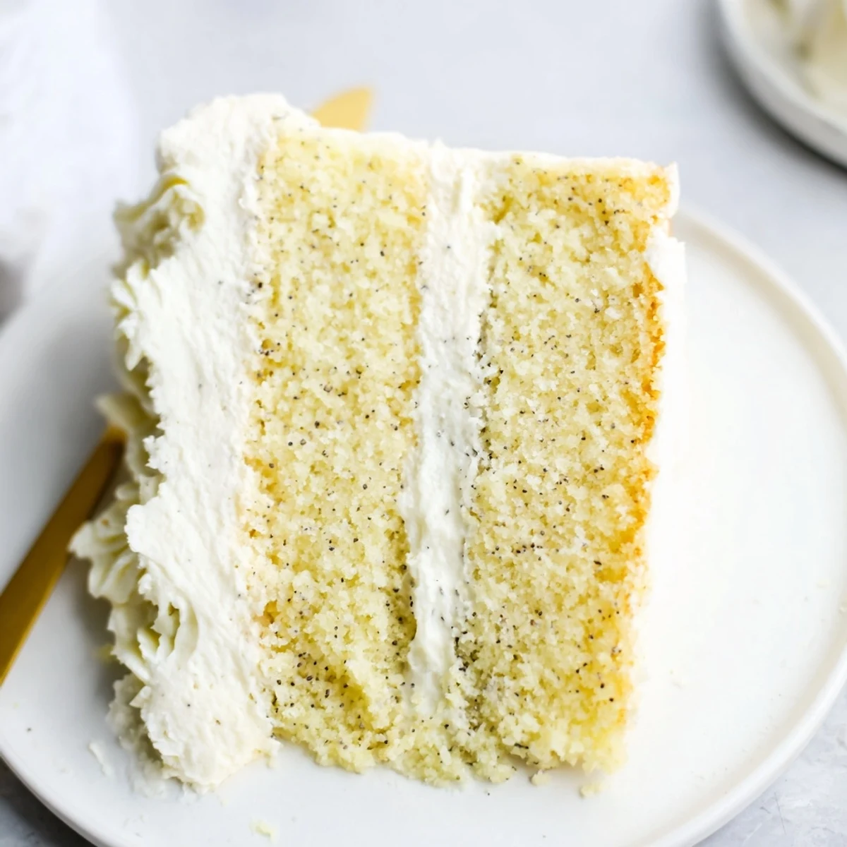 Vanilla bean birthday cake with buttercream frosting topped with colorful sprinkles on a serving plate