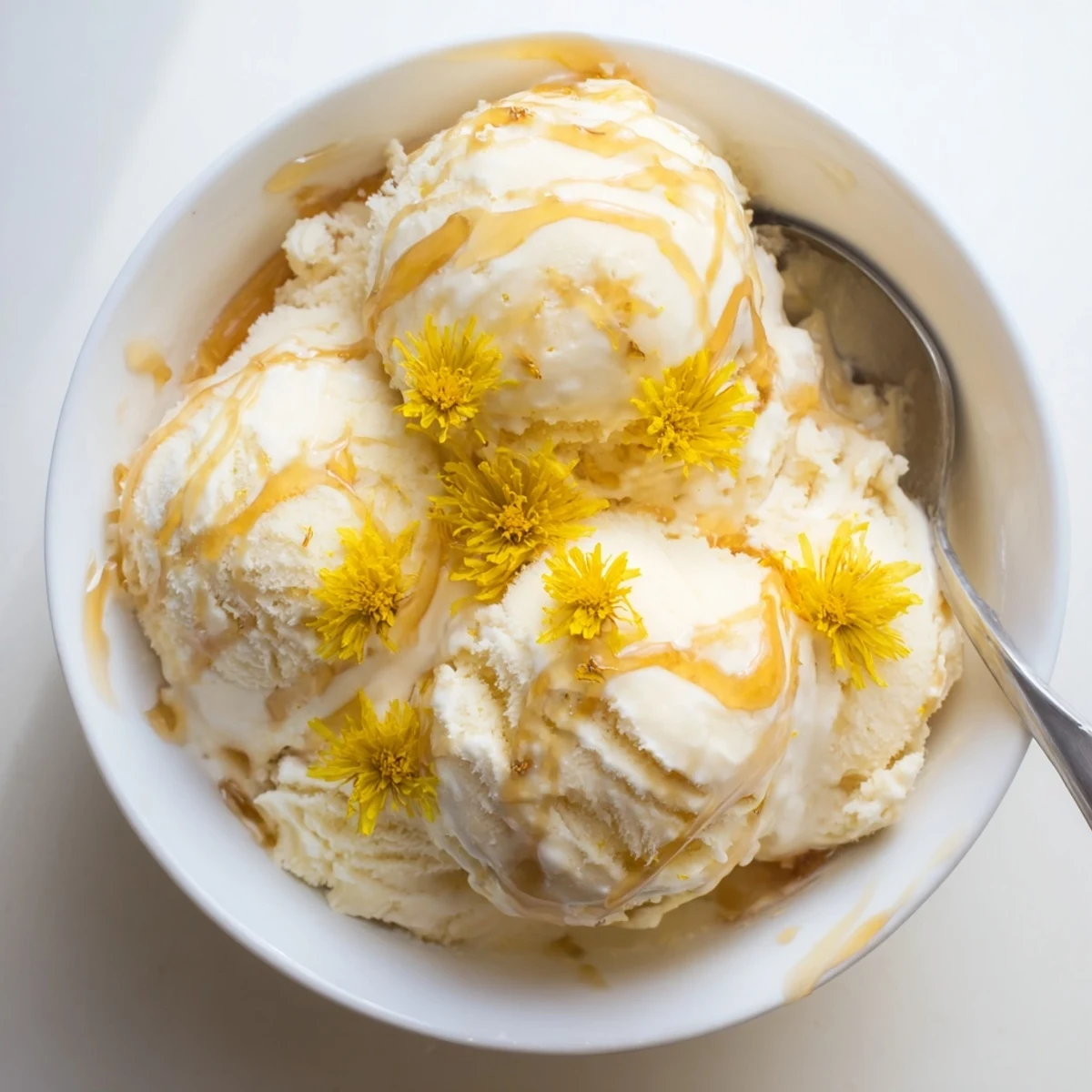 Creamy dandelion honey ice cream scooped into a bowl with golden honey drizzled on top