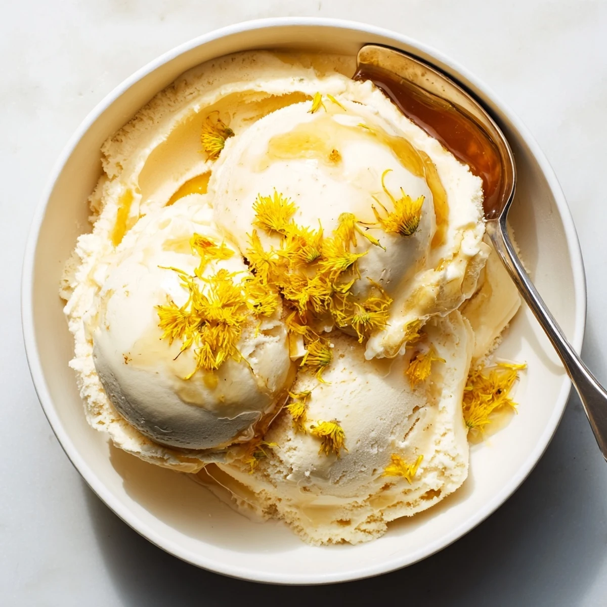 Velvety homemade dandelion honey ice cream served in a chilled glass bowl for summer dessert