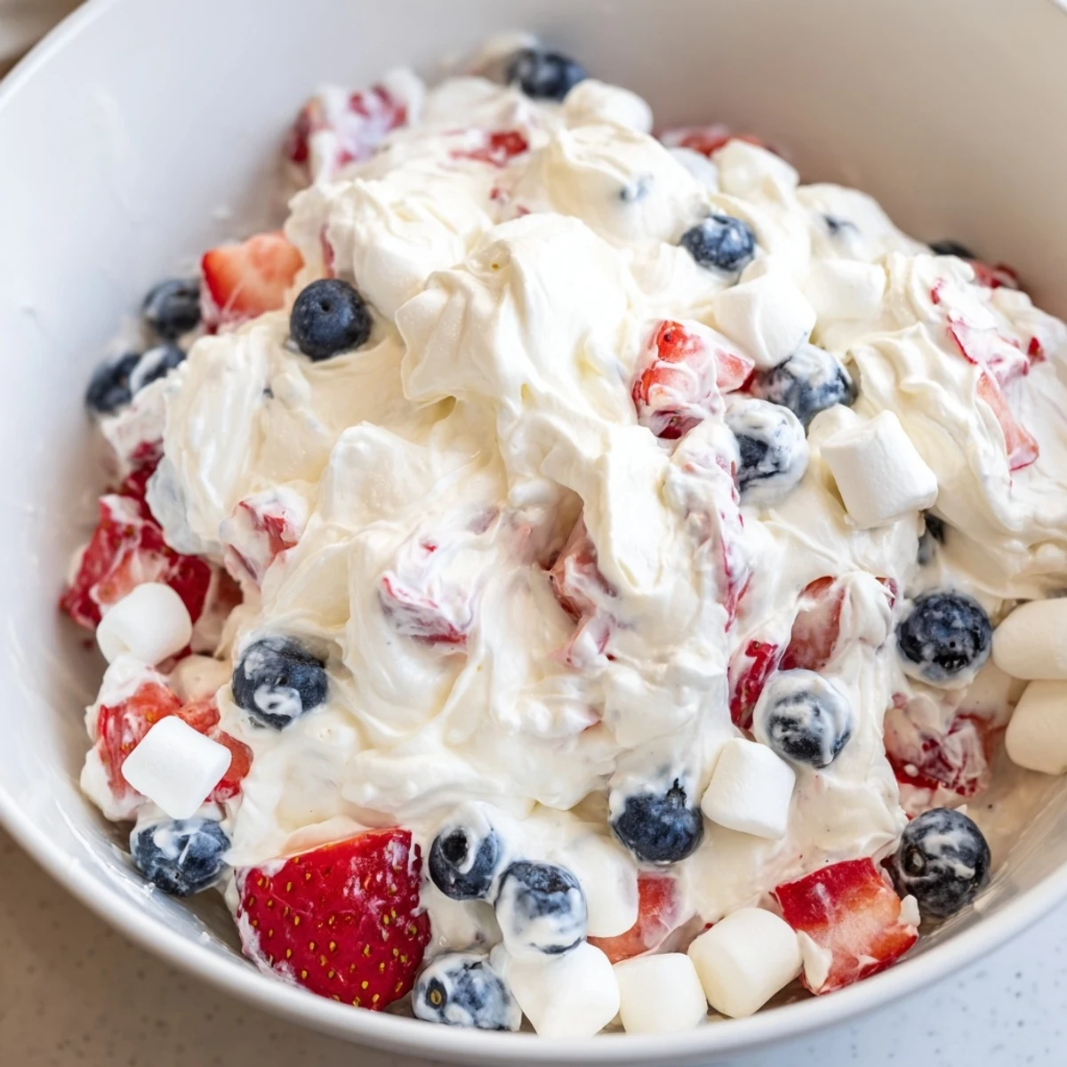 Luscious Red White Blue Cheesecake Salad scooped into individual dessert cups with berry garnish