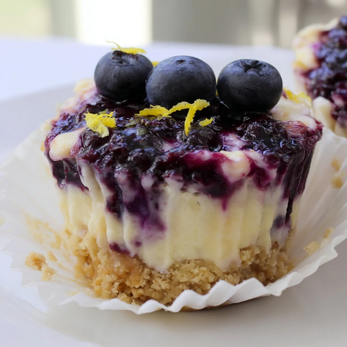 Mini Lemon Blueberry Cheesecakes topped with glossy berry compote in a rustic muffin tin