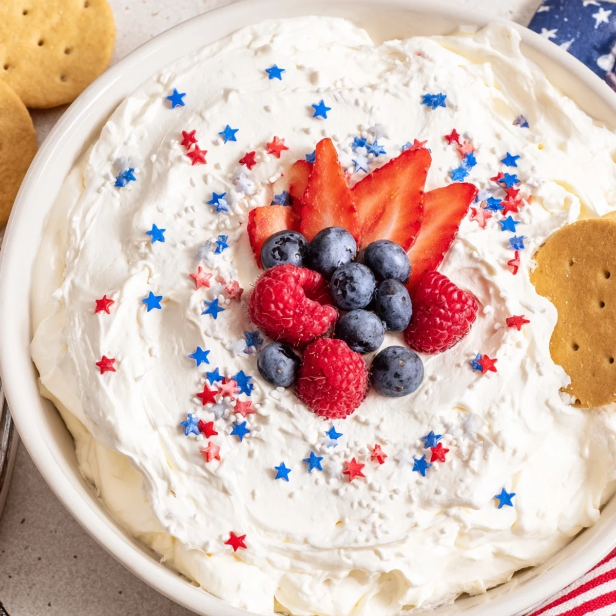 Creamy Star Spangled Cheesecake Dip topped with ripe berries and sprinkles
