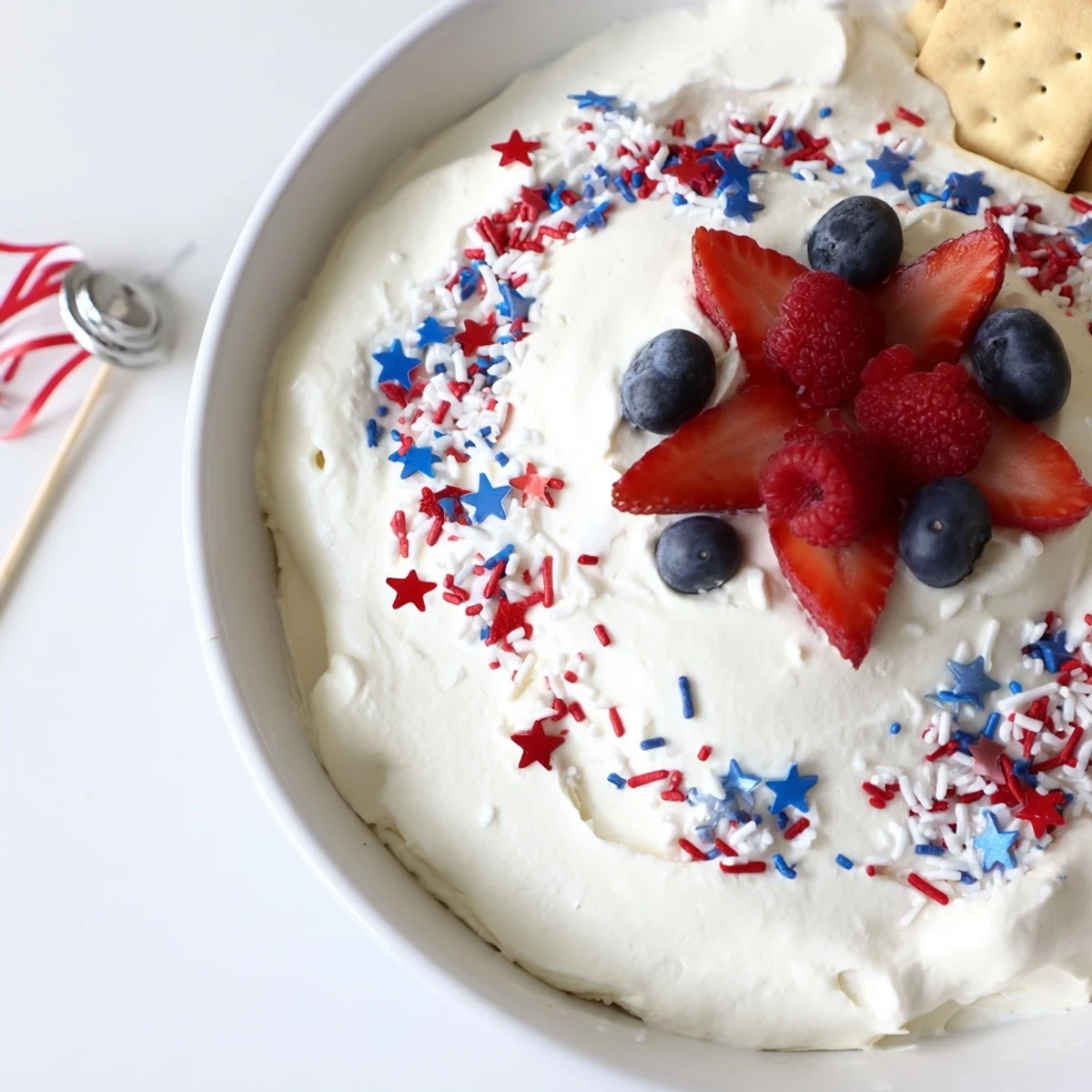 Patriotic Star Spangled Cheesecake Dip fluffy and chilled, garnished with strawberries and blueberries