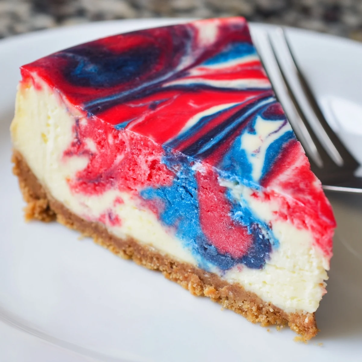 Patriotic Swirl Cheesecake with glossy red and blue marbling, chilled to serve  