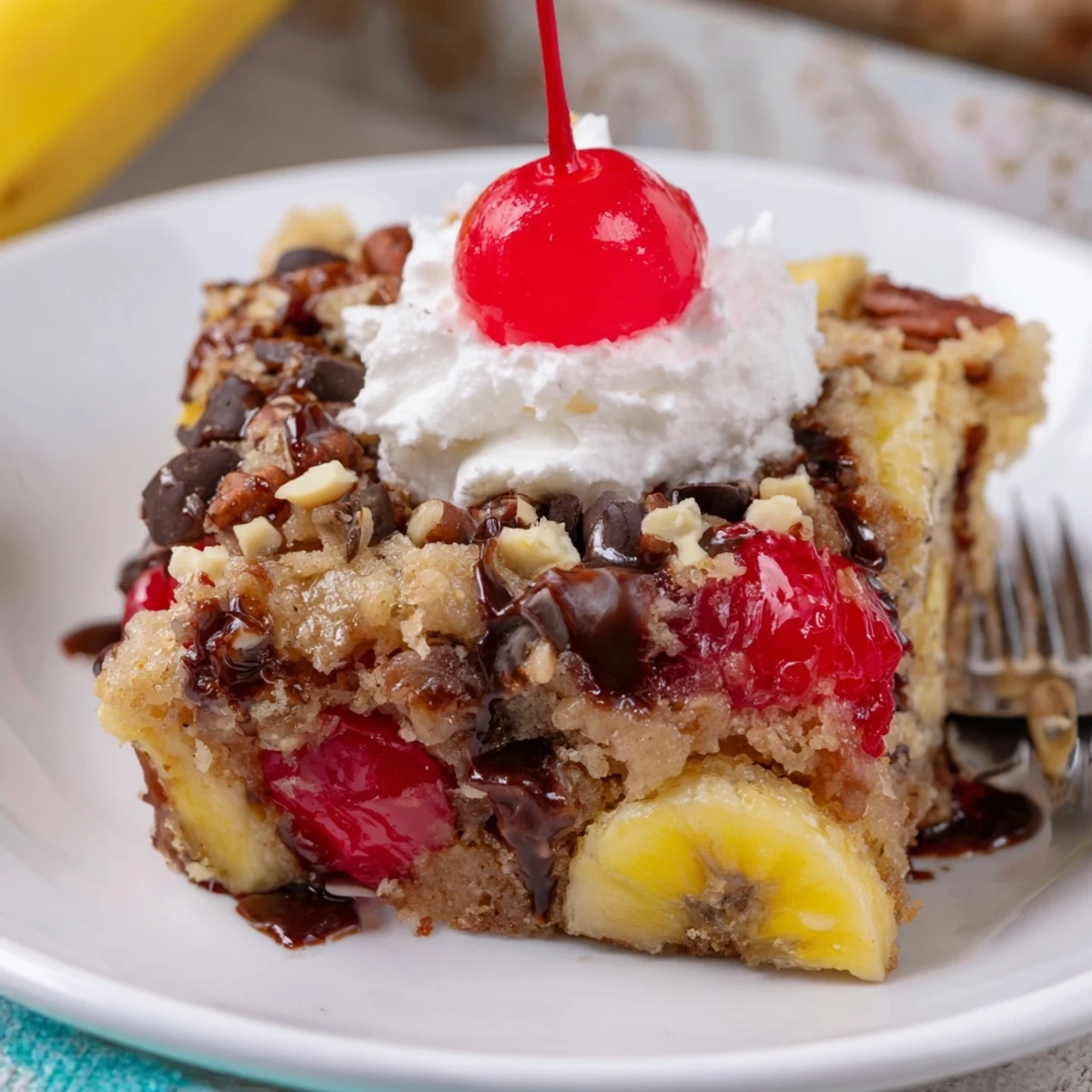 Sliced bananas and cherries peeking through Banana Split Dump Cake, drizzled with chocolate