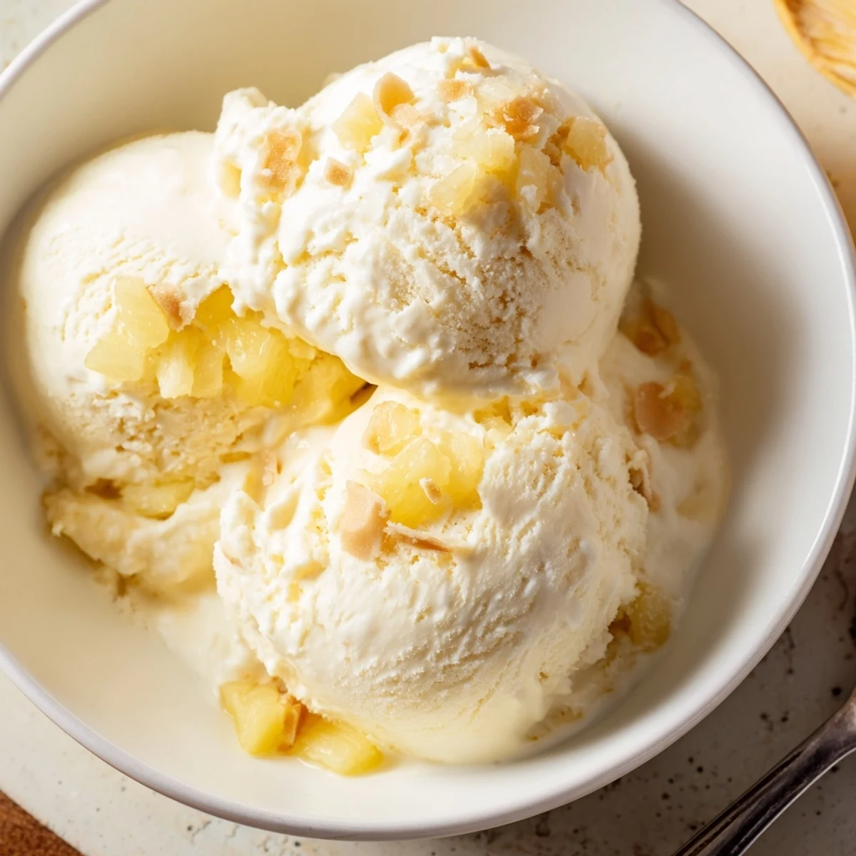 Scoops of Creamy Pineapple Ice Cream topped with toasted coconut flakes