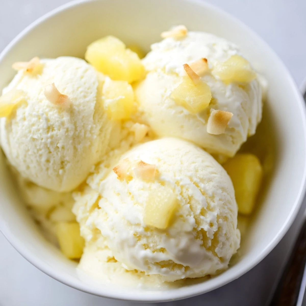 Homemade Creamy Pineapple Ice Cream cooling in bowl, bright pineapple aroma