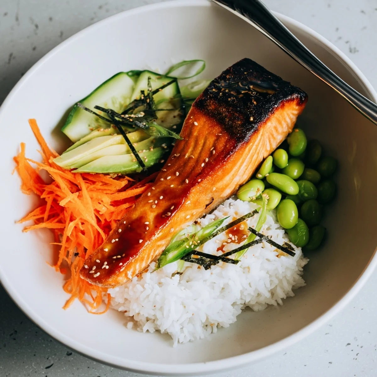 Pan-seared Crispy Salmon And Rice Bowl topped with creamy avocado and sesame