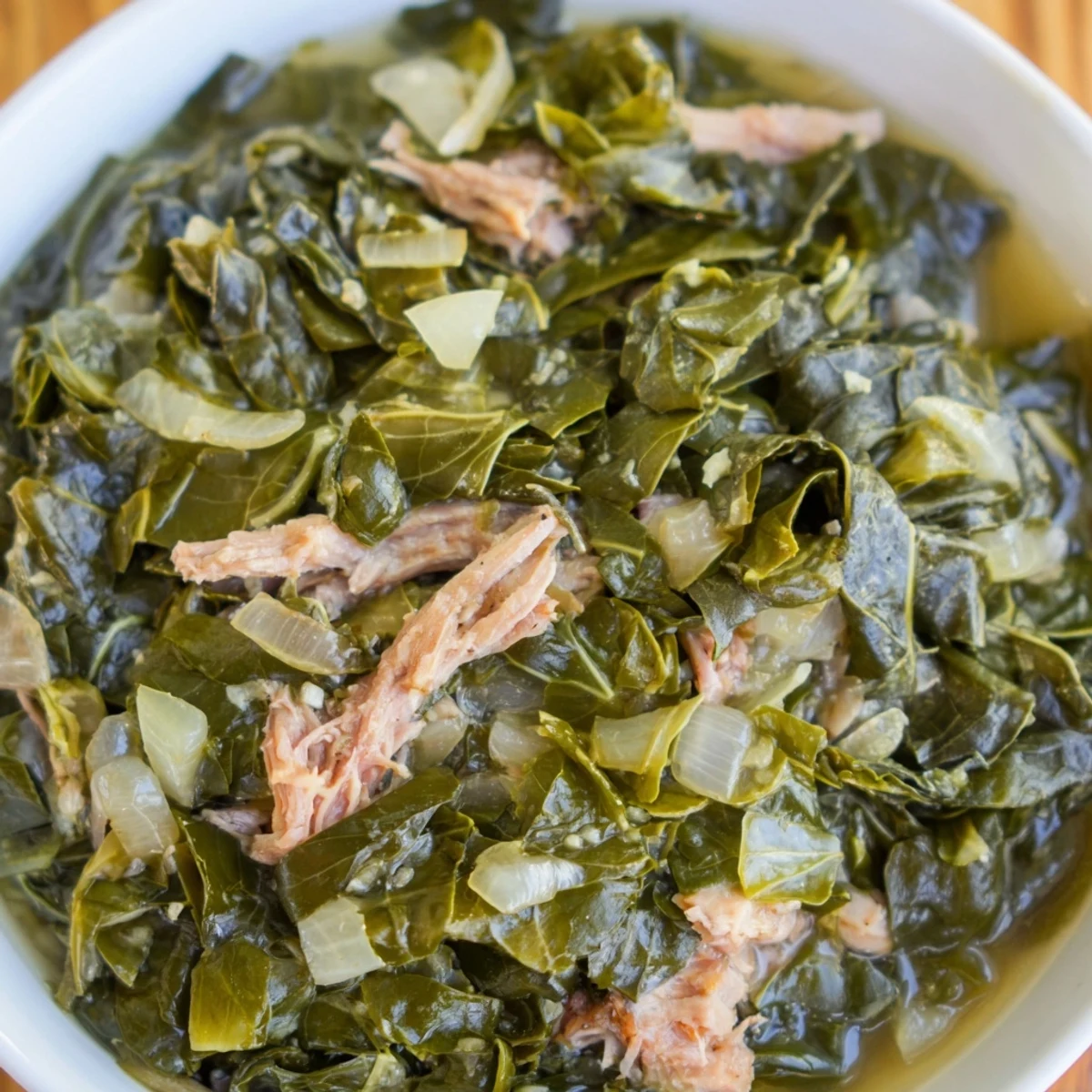 Hearty bowl of classic collard greens, slow-simmered with smoky flavors and perfect for scooping with warm cornbread.