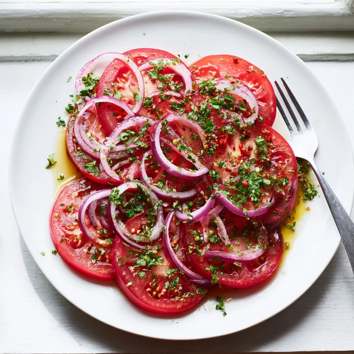 Fresh tomato and onion salad with light vinaigrette drizzled over crisp sliced vegetables