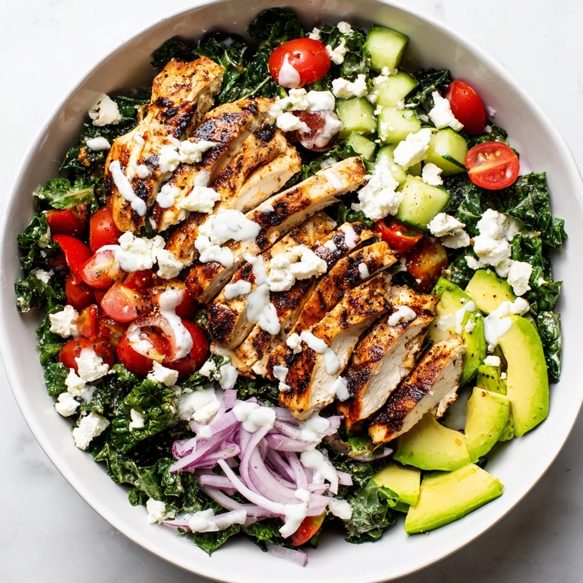 Juicy seasoned chicken atop massaged kale greens with cherry tomatoes, cucumber, and crumbled feta cheese