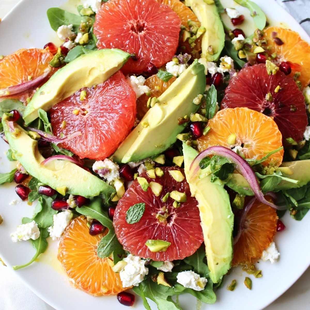 Colorful Mediterranean citrus salad garnished with pomegranate arils, mint, and toasted pistachios