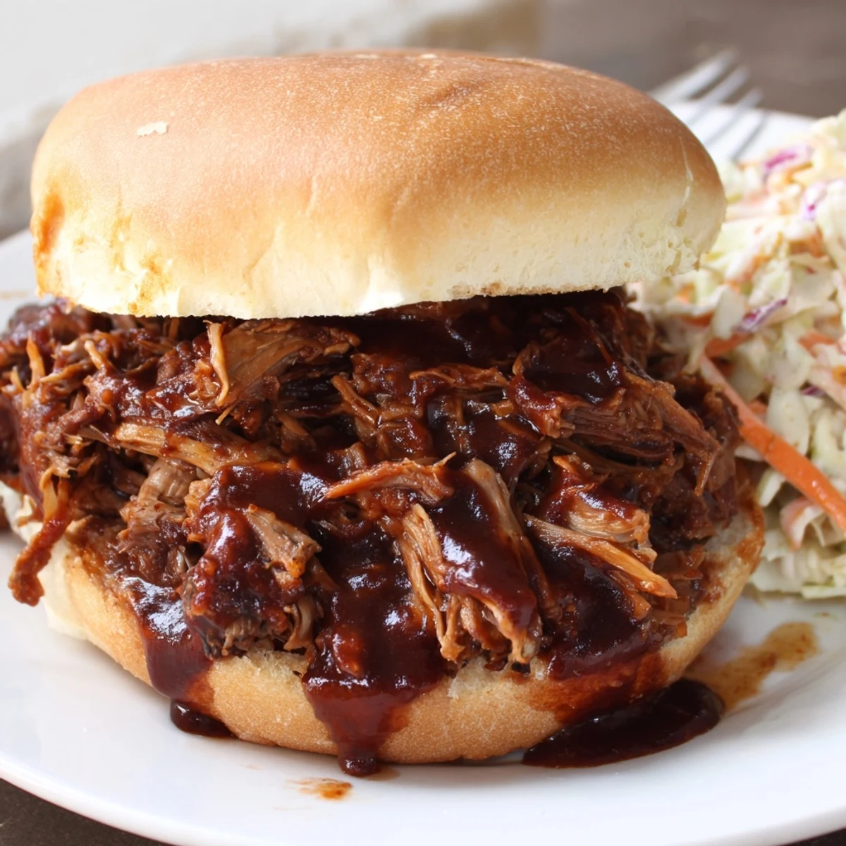 Slow Cooker BBQ Pulled Beef piled high on a toasted bun with creamy coleslaw