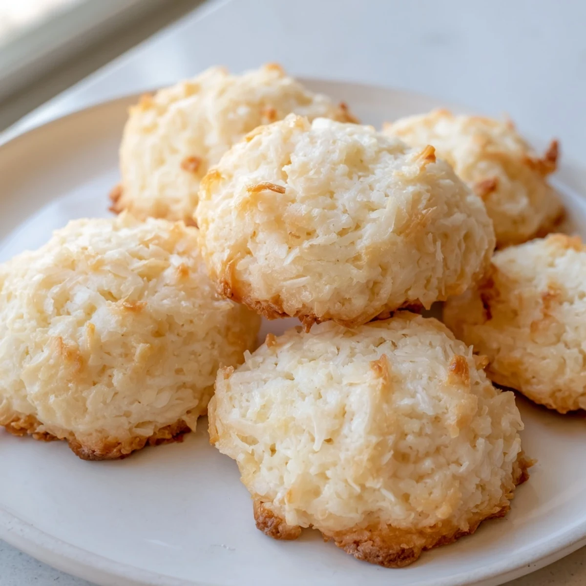 Soft and buttery coconut cookies arranged on a rustic ceramic serving plate