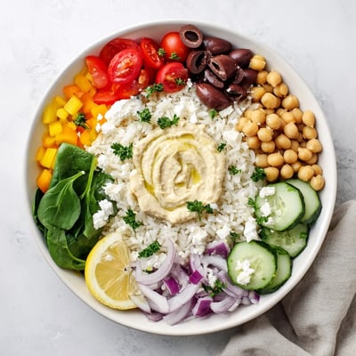 Fluffy rice base layered with crisp cucumbers, tomatoes, olives, and creamy feta in Mediterranean rice bowl