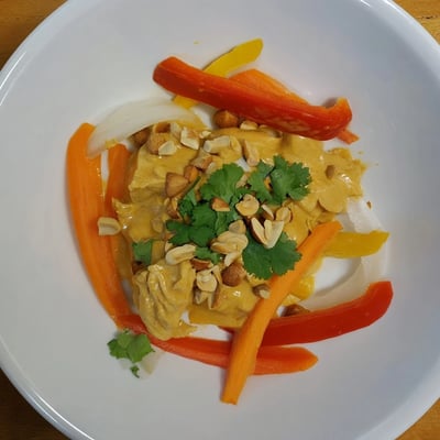 Creamy peanut sauce coats tender chicken thighs with bell peppers and fresh cilantro garnish