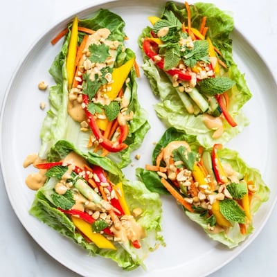 Vibrant cabbage wraps showcasing sweet mango strips and crisp veggies topped with tangy peanut dressing