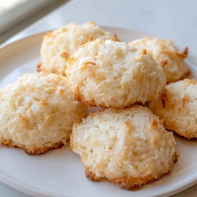 Soft and buttery coconut cookies arranged on a rustic ceramic serving plate
